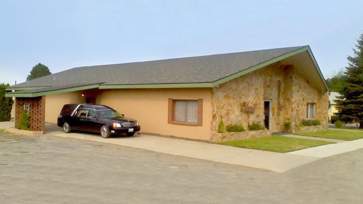 Front exterior with hearse at Strate Funeral Home.
